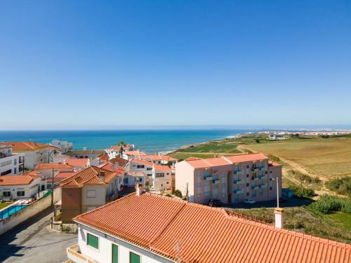 a group of buildings with the ocean in the background at Tilli'n'Joe's Beach House in Atouguia da Baleia