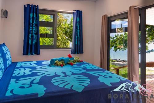 - une chambre avec un lit bleu orné de fleurs dans l'établissement Matira Beach Raitea 2, à Bora Bora