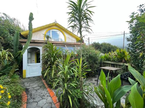 een klein huis met een witte deur in een tuin bij Sunset Nest in Ponta Delgada