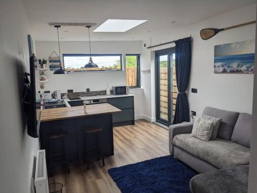 a living room with a kitchen and a couch at Modern cosy apartment walking distance to many cove beaches and coast path walks as well as the famous Helford river in Falmouth