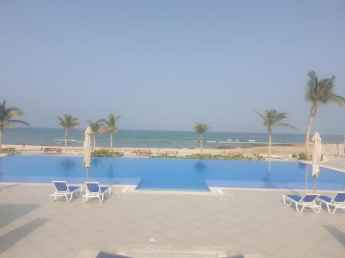 una piscina con sillas y una playa en Sunrise Sifah, en As Sīfah