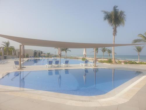 una gran piscina con sillas y palmeras en Sunrise Sifah, en As Sīfah