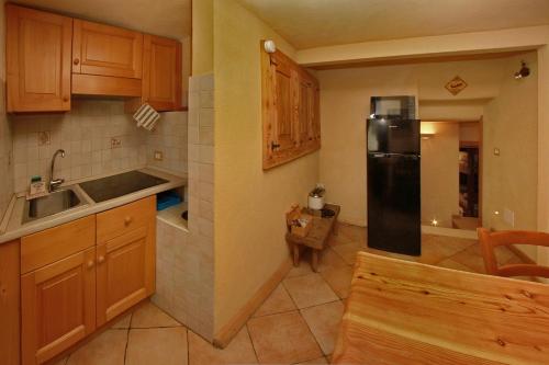 a kitchen with wooden cabinets and a black refrigerator at Eydappartamenti in Sauze dʼOulx