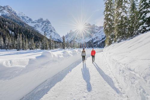 twee mensen lopen over een met sneeuw bedekte weg bij Residence Grüne Laterne - Lanterna Verde in Sesto