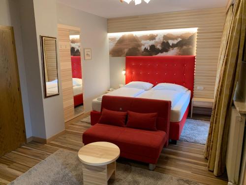 - une chambre avec un lit et un canapé rouge dans l'établissement Ruster Resort, à Lagundo