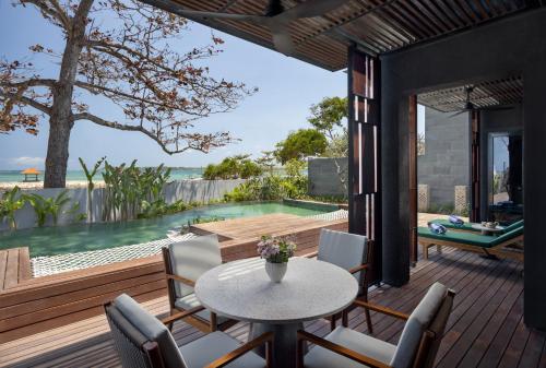 patio ze stołem i krzesłami oraz basenem w obiekcie Sumitra Luxury Villas A Pramana Experience w mieście Sanur