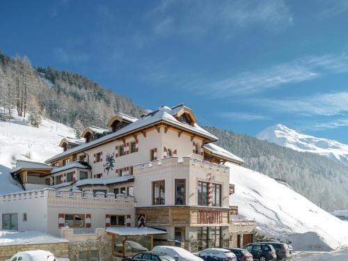 オーバーグルグルにあるBurghotel Alpenglühnの雪の中に車が停まった建物