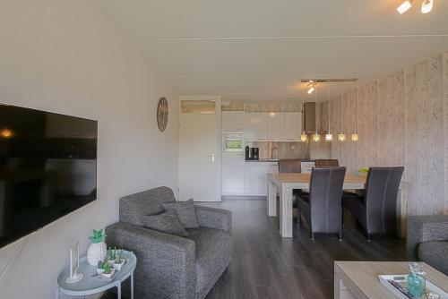 Il comprend un salon et une cuisine avec une table et des chaises. dans l'établissement Beach Appartement 14 - Callantsoog, à Callantsoog