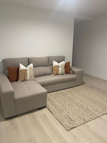 ein graues Sofa mit Kissen darauf im Wohnzimmer in der Unterkunft Modern Spacious Apartment in Entroncamento