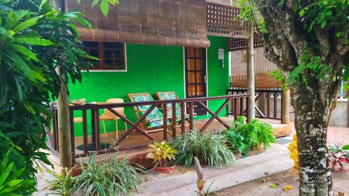 une maison avec un mur vert et des chaises devant elle dans l'établissement Fern Lodge Self Catering, à La Digue