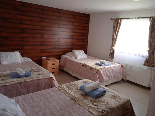 Cette chambre comprend 3 lits et une fenêtre. dans l'établissement Hostal JC, à Puerto Natales