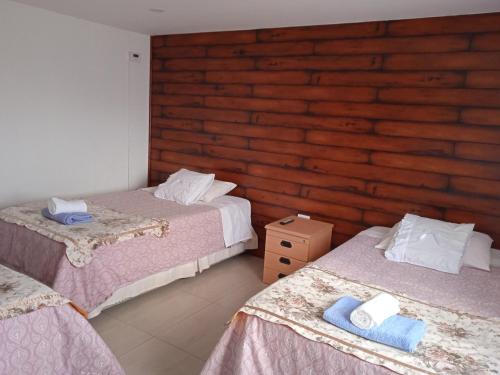 - une chambre avec 2 lits et un mur en bois dans l'établissement Hostal JC, à Puerto Natales