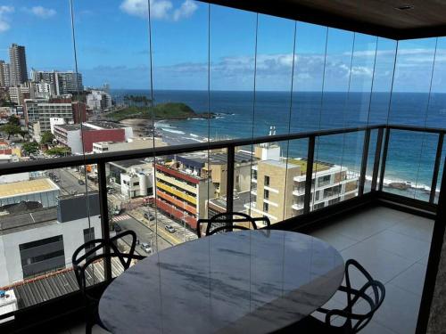 - une table sur un balcon avec vue sur l'océan dans l'établissement Salvador Farol da Barra N903 Apartamento Vista Mar, à Salvador