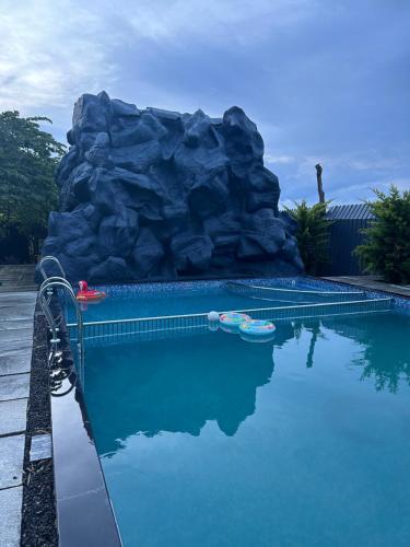 a swimming pool with a rock in the background at Chalets Resort Masinagudi in Ooty