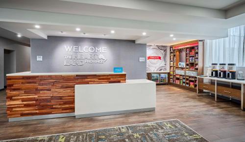 a store with a welcome sign and a white counter at Hampton Inn By Hilton Hamilton in Hamilton