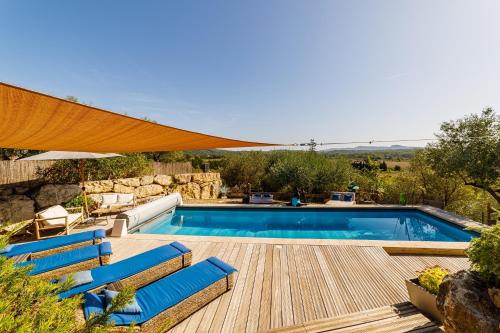 uma piscina com cadeiras azuis e um guarda-sol em O PATIO DU MAS em Callas