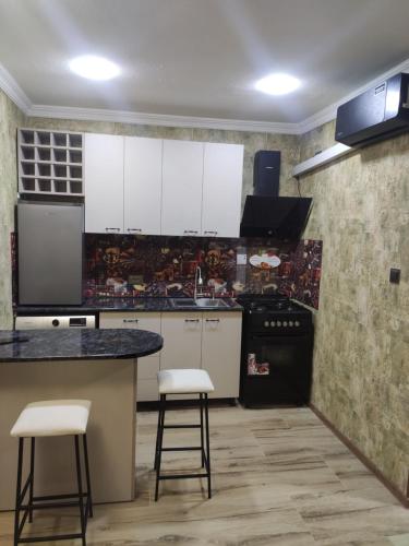 a kitchen with white cabinets and a counter and stools at gabro in Mtskheta