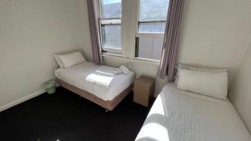 een kleine kamer met 2 bedden en een raam bij Beachside Budget Rooms in Kiama