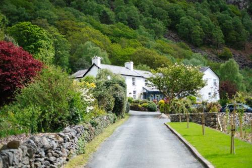 una calle en un pueblo con casas y un muro de piedra en Tŷ Afon - River House, en Beddgelert