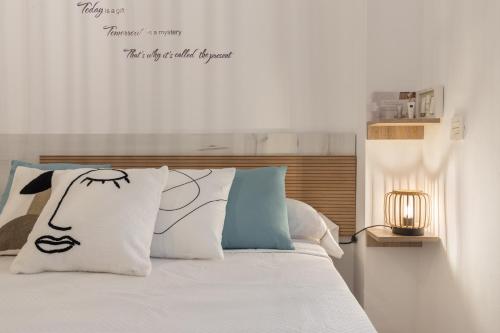 una camera da letto con un letto con lenzuola bianche e cuscini blu di APARTAMENTOS NURIA 19 a Granada