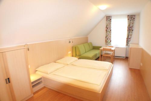 1 dormitorio con 1 cama y 1 silla verde en Jugendgästehaus St. Gilgen, en Sankt Gilgen