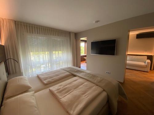 - une chambre avec un grand lit blanc et une télévision dans l'établissement Hotel Villa Elben Lörrach bei Basel, à Lörrach