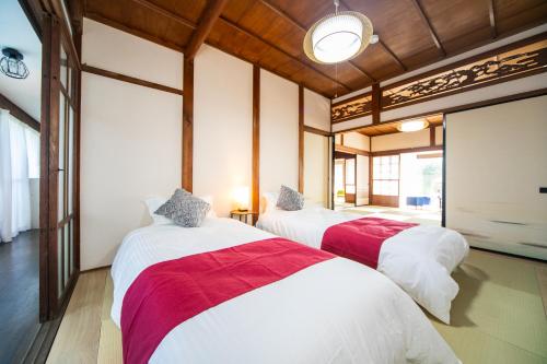 NagashimaにあるNagashima Traditional Houseの白と赤のシーツが備わる客室のベッド2台