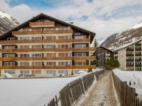 um edifício na neve com uma cerca em Charmjl, Haus Granit, 6 Personen em Zermatt