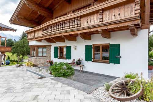 une maison avec des fenêtres vertes et un toit en bois dans l'établissement Ferienbauernhof Stallhäusl, à Fieberbrunn