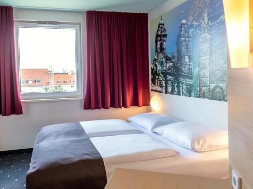 a bedroom with a bed and a window with red curtains at B&B Hotel Nürnberg-City in Nürnberg