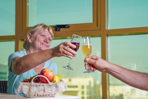 2 persone che tengono bicchieri di vino accanto a un cesto di frutta di AG Hotel a Abu Dhabi