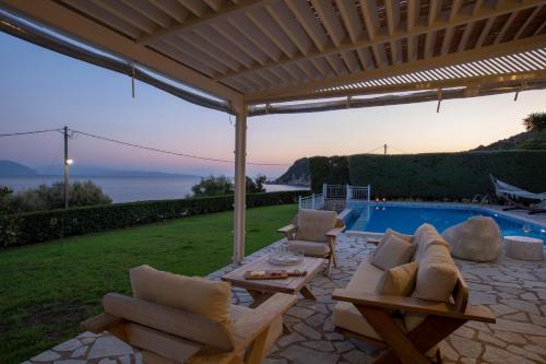 een patio met een tafel en stoelen en een zwembad bij Ionian Calm Villas in Vasiliki