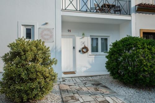 una porta bianca di una casa con due cespugli di Raminhos Guest House a Vila Nova de Milfontes