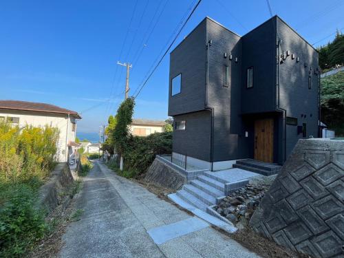 une maison noire avec une porte dans une rue dans l'établissement Keshiki 淡路島, à Awaji