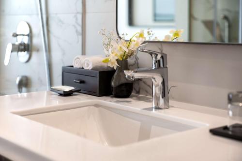 a bathroom sink with a mirror and a vase of flowers at Country Inn & Suites By Radisson Navi Mumbai in Navi Mumbai