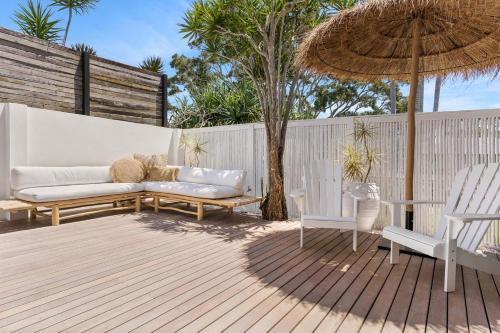 un patio con divano, sedie e ombrellone di Salta a Byron Bay