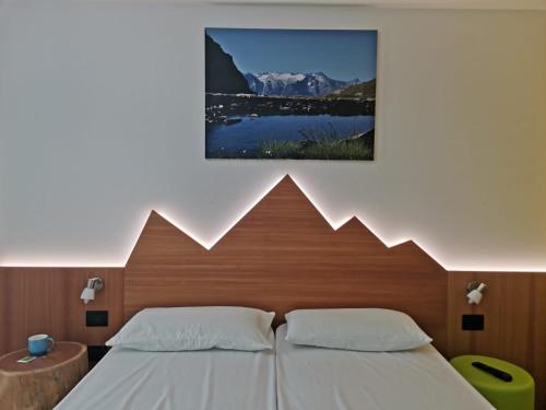 1 dormitorio con 1 cama con una foto en la pared en Alpencolor Hotel Tonale, en Passo del Tonale