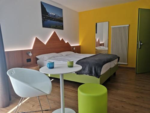 1 dormitorio con 1 cama, mesa y sillas en Alpencolor Hotel Tonale, en Passo del Tonale