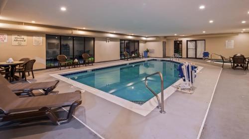 - une piscine dans un hôtel avec des chaises et une table dans l'établissement Chicago Southland Hotel, à Oak Forest