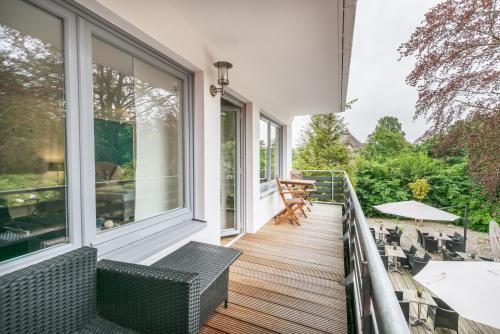 balcone con sedie, tavoli e finestre di Das Frühstückshotel Sankt Peter-Ording a Sankt Peter-Ording