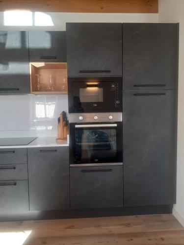 a kitchen with gray cabinets and an oven at Appartamento Vale e Schena Cortina D'Ampezzo in San Vito di Cadore