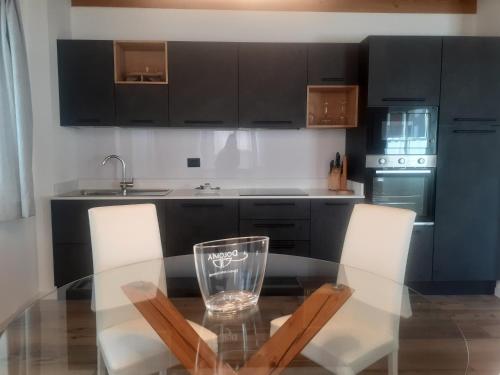 a kitchen with a glass table and two chairs at Appartamento Vale e Schena Cortina D'Ampezzo in San Vito di Cadore