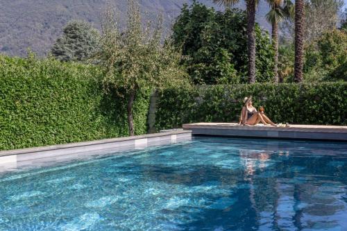 Eine Frau und ein Hund, die neben einem Pool sitzen. in der Unterkunft Ascona Lodge, Pool & Garden Retreat in Ascona