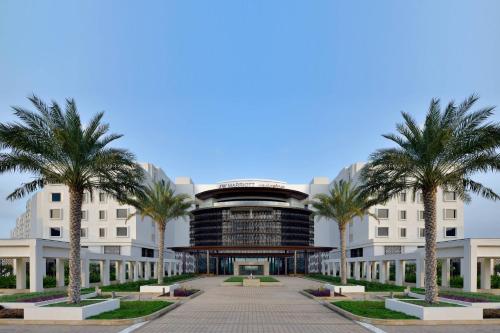 un edificio con palme di fronte ad esso di JW Marriott Hotel Muscat a Mascate