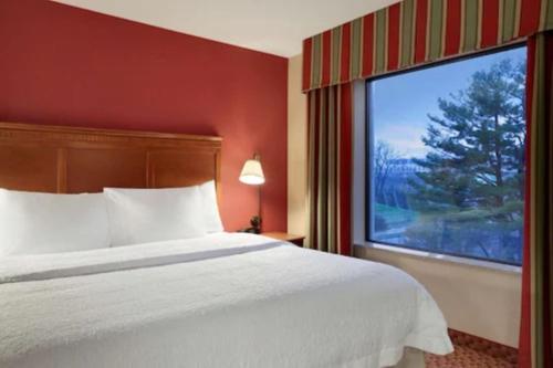 a hotel room with a bed and a large window at Hampton Inn & Suites East Hartford in East Hartford