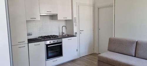 uma cozinha com armários brancos e um forno com placa de fogão em Maso kreuzberg- Monolocale 3- vista montagne em Trento