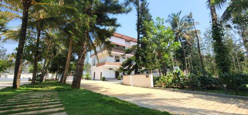 un edificio con palme di fronte a un marciapiede di Mazra Retreat, Coorg Kushālnagar a Kushalnagar