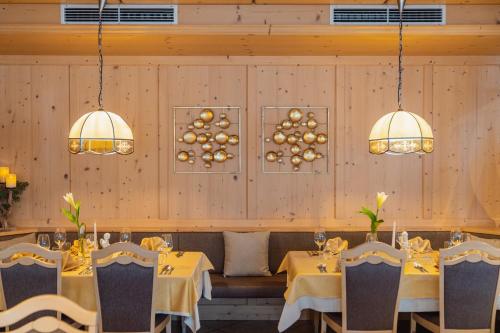 een eetkamer met 2 tafels en 2 kroonluchters bij Hotel Christoph in Valdaora