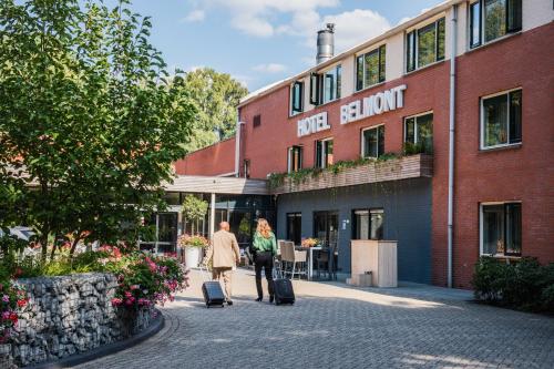 Due persone che camminano per una strada di fronte a un edificio di 50|50 Hotel Belmont a Ede