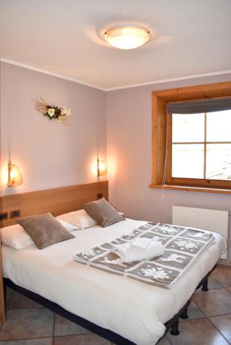 a bedroom with a large white bed and a window at Appartamento Trela 2 in Livigno